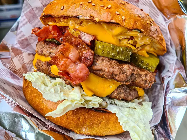 Dvojitý burger so slaninou a cheddarom zabalený v alobale